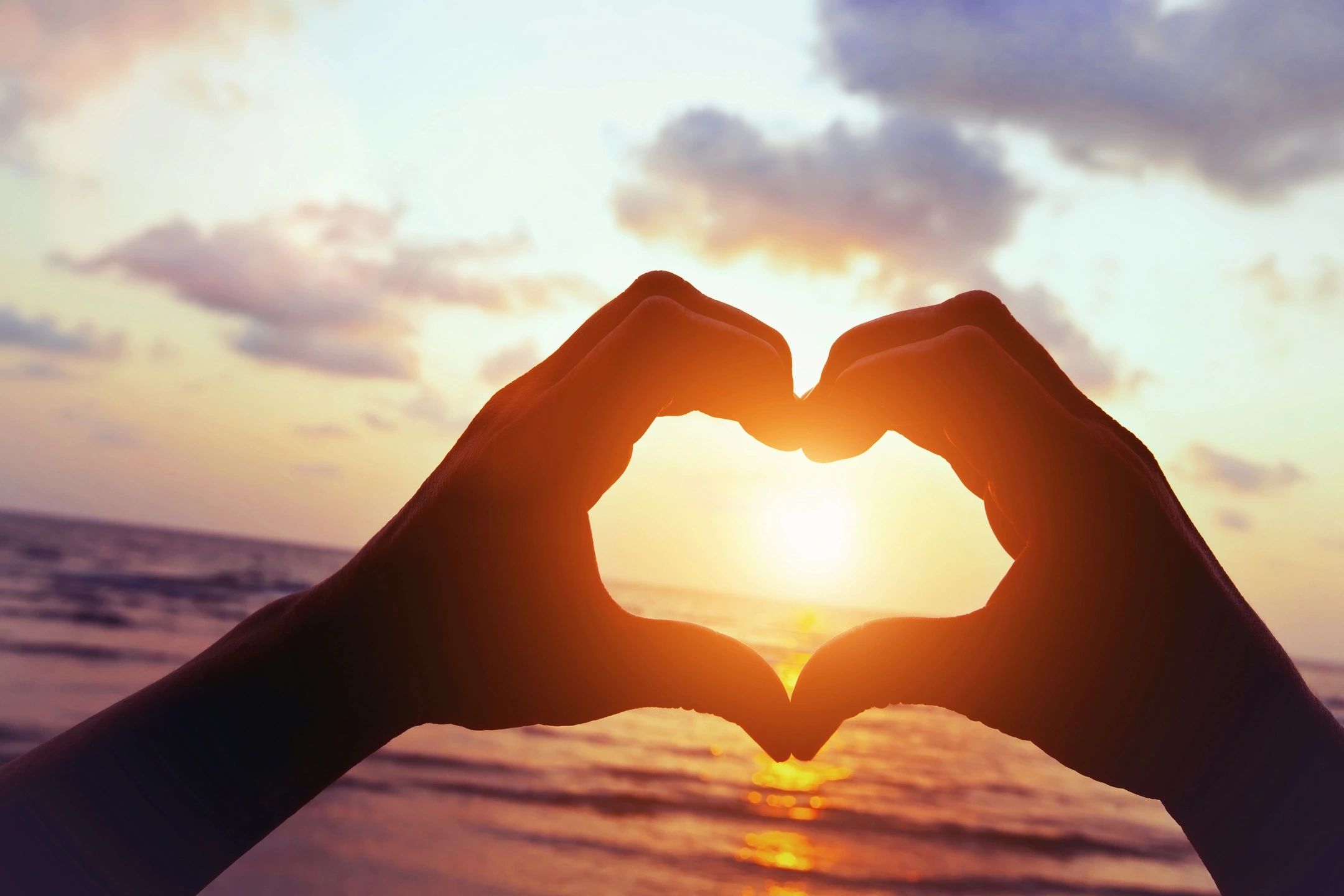 Heart hands silhouette at golden sunset