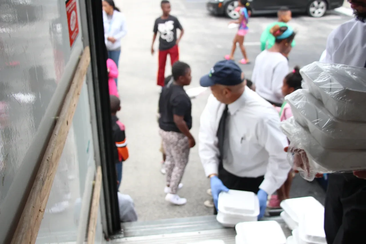 Volunteer handing food containers to community members from truck