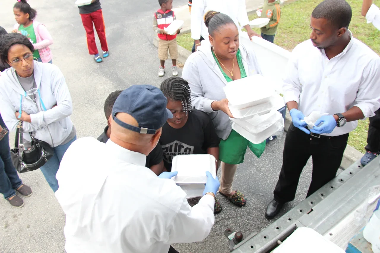 Volunteers passing food containers to community members from truck