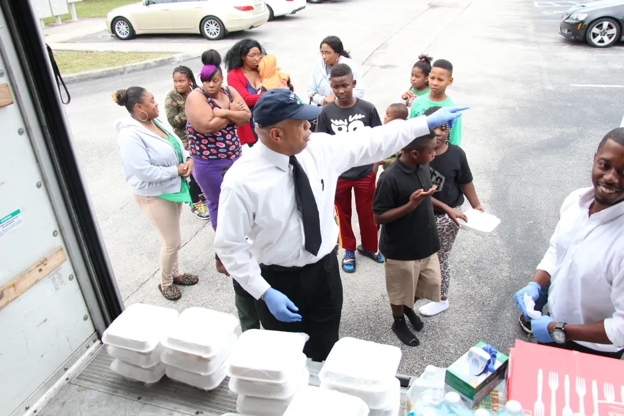 Volunteer directing crowd at food distribution from U-Haul truck
