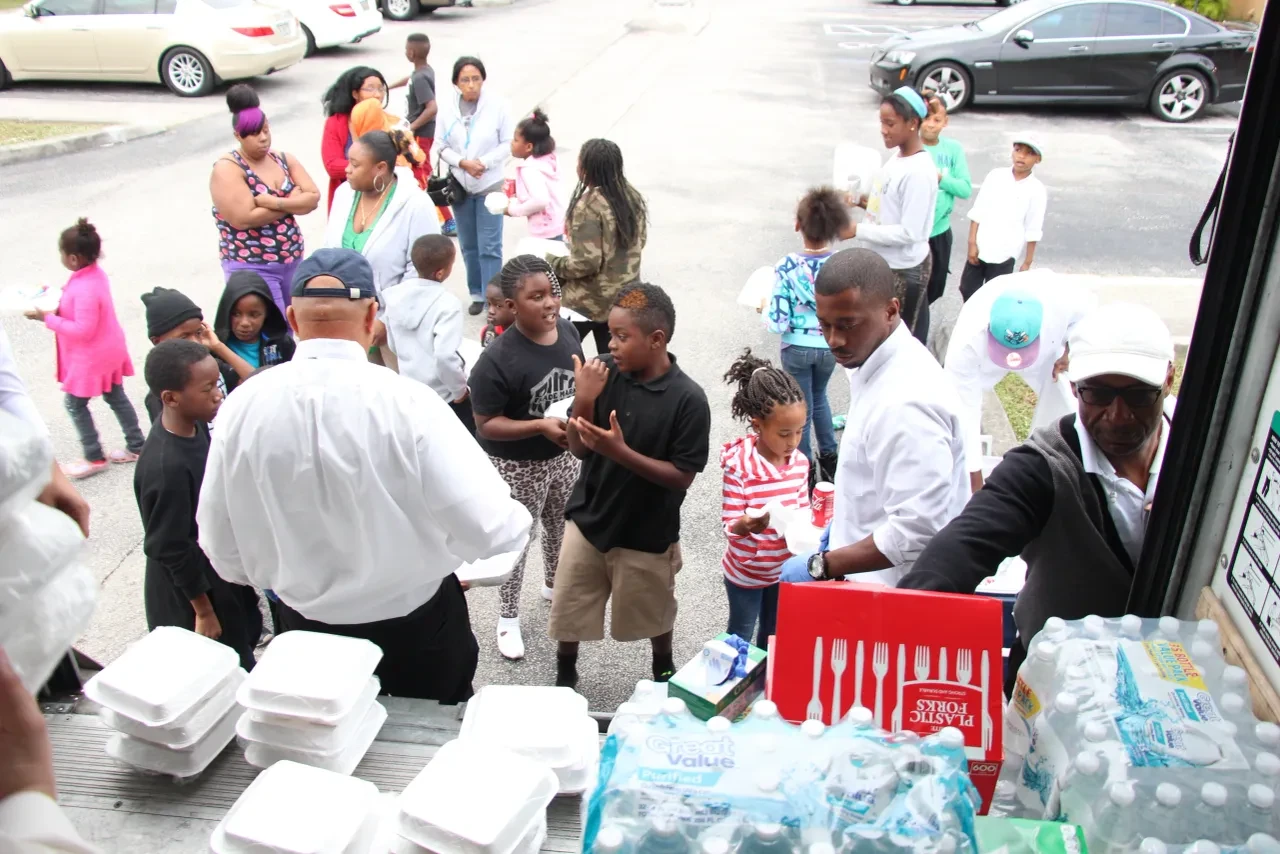 Volunteers serving large crowd of children and families from U-Haul truck