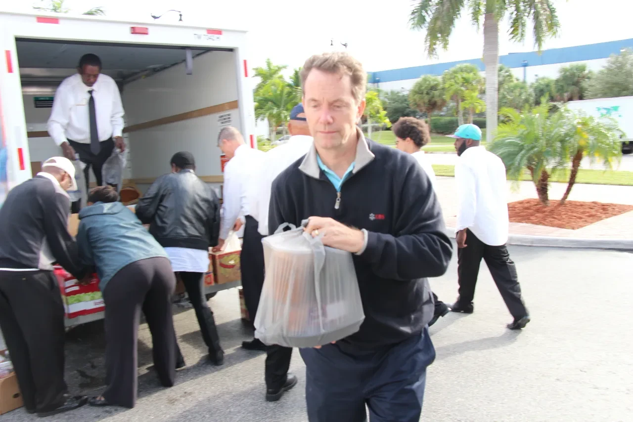 Volunteer carrying food bag away from U-Haul truck at distribution event
