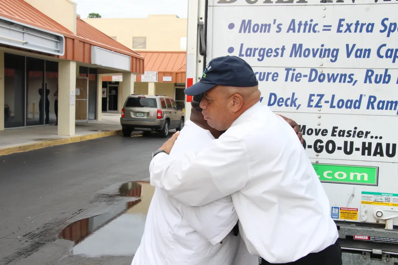Two men embracing next to U-Haul truck at community event