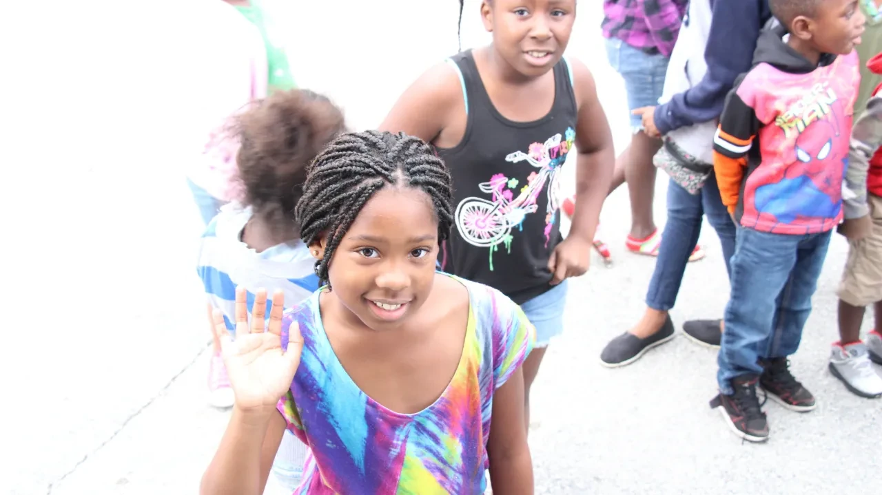 Young girl waving at community outreach event with children