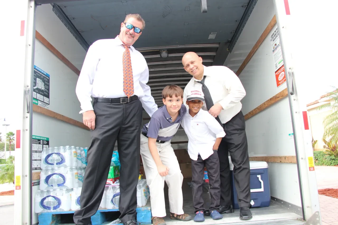 Two adults and two children posing inside U-Haul truck with water supplies