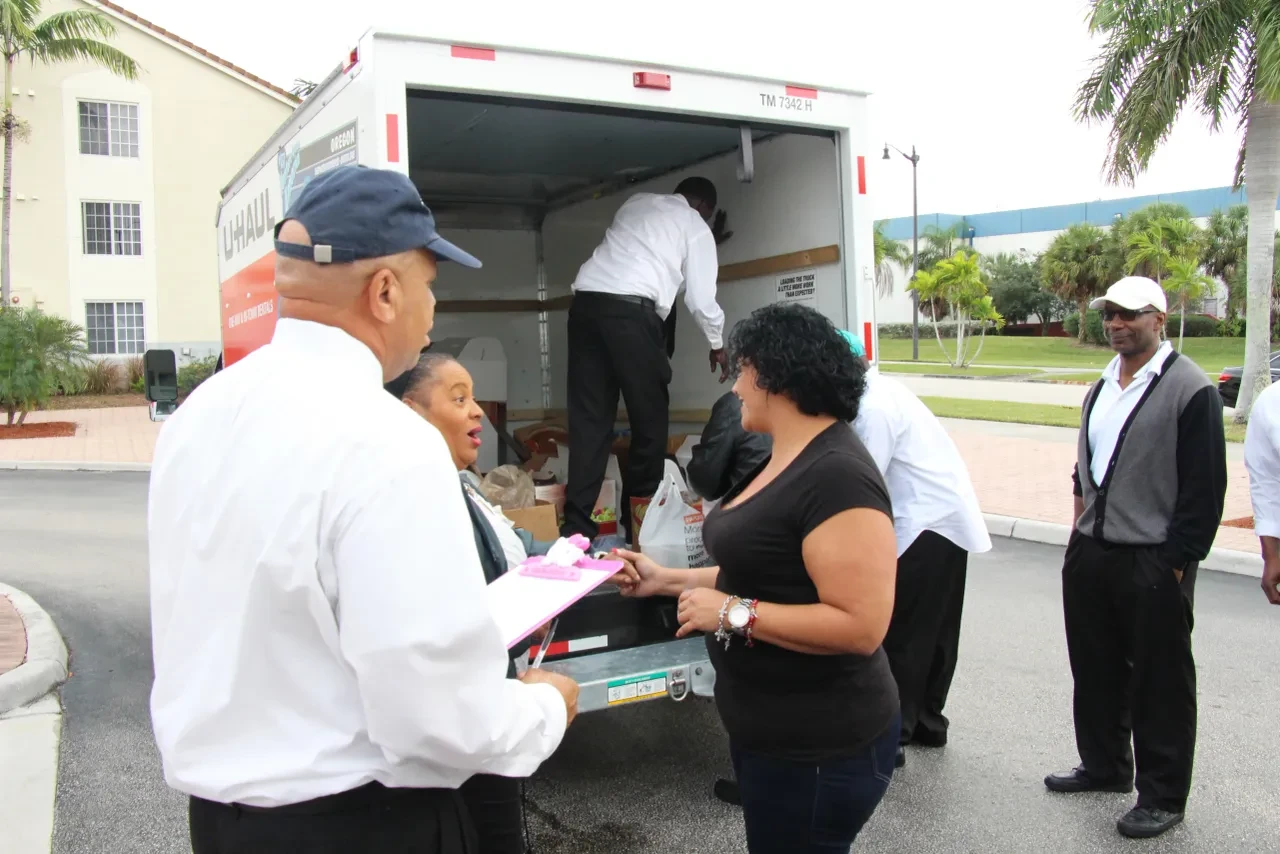 Volunteers coordinating food distribution at U-Haul truck with clipboard