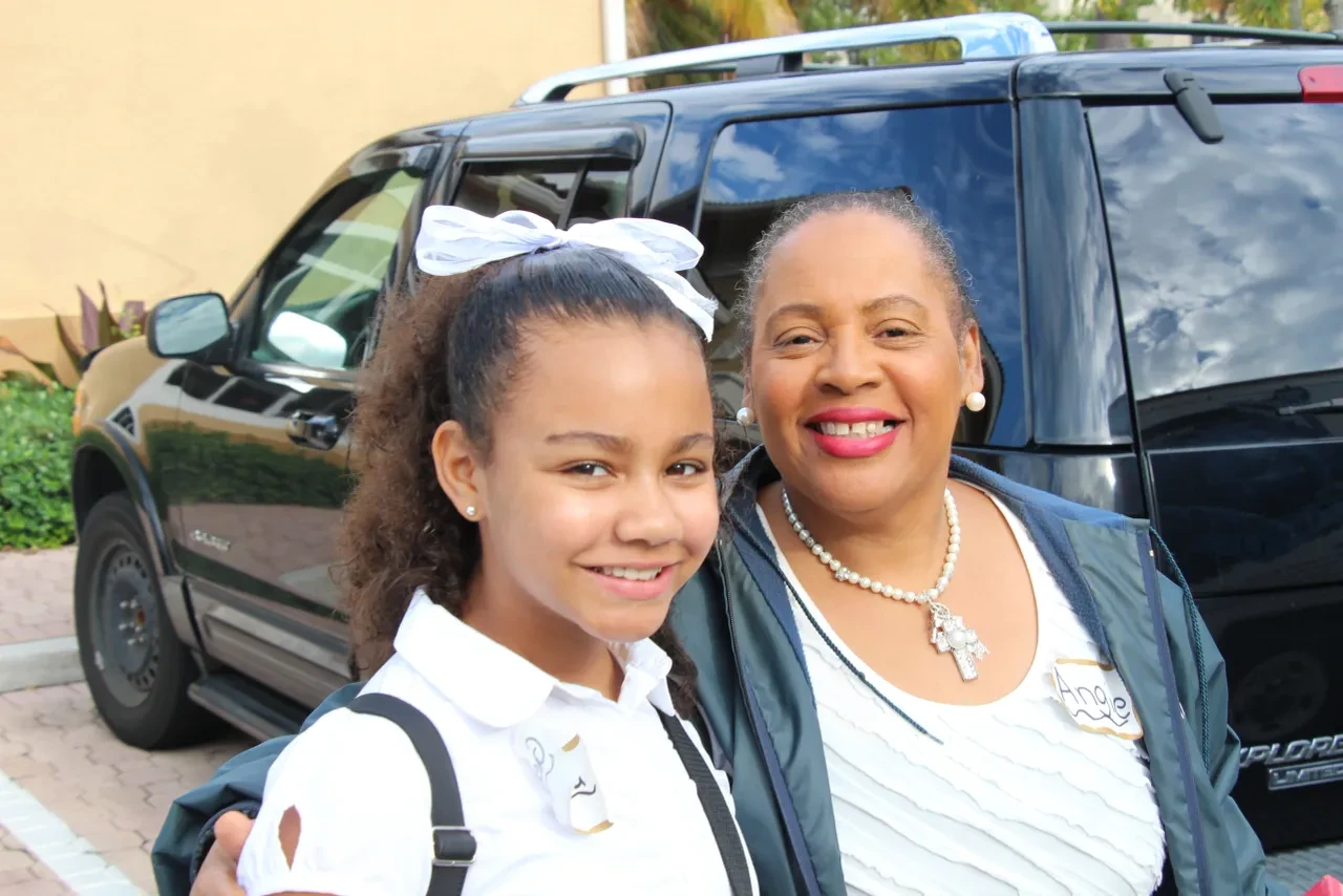 Young girl and woman smiling together in parking lot at community event