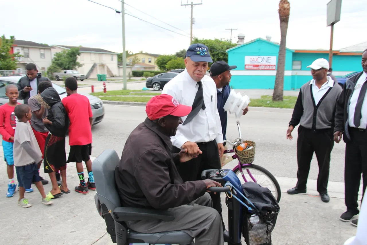 Volunteer assisting elderly man on mobility scooter at community outreach