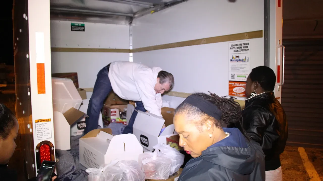 Volunteers sorting Golden Corral boxes inside U-Haul truck at night