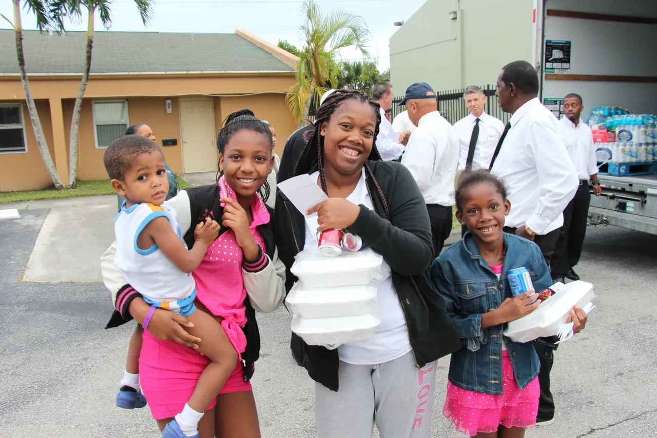 Family smiling with food containers at community distribution event