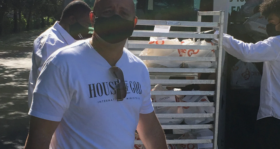 Three masked volunteers carrying Golden Corral bags across sunny parking lot