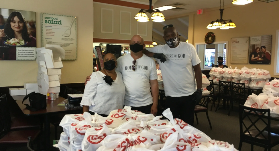 Three volunteers in House of God shirts posing at Golden Corral with food donations