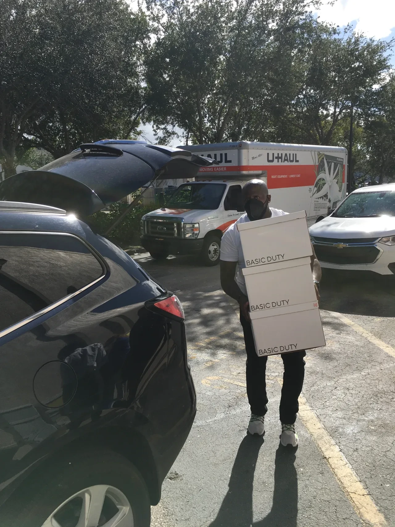 Volunteer carrying Basic Duty boxes in parking lot with U-Haul truck
