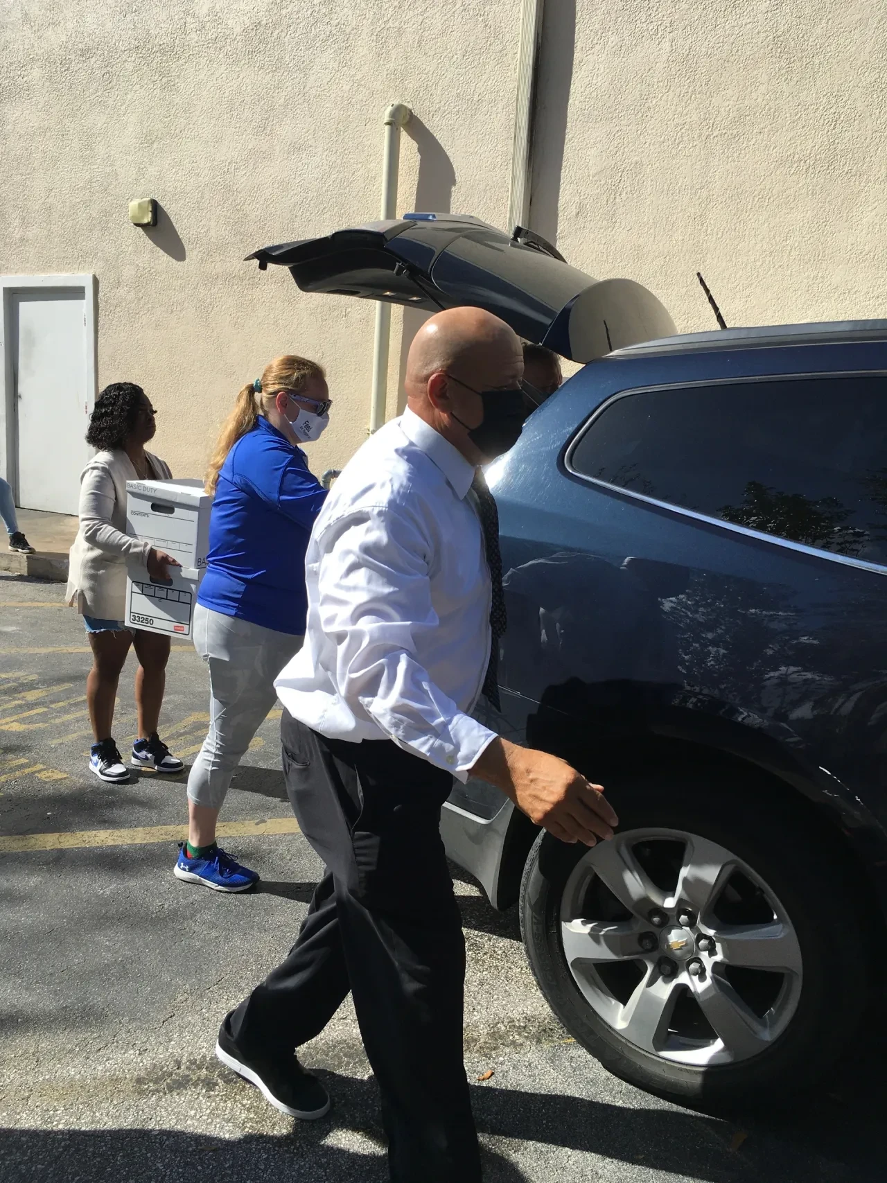 Volunteers loading boxes into car trunk in parking lot