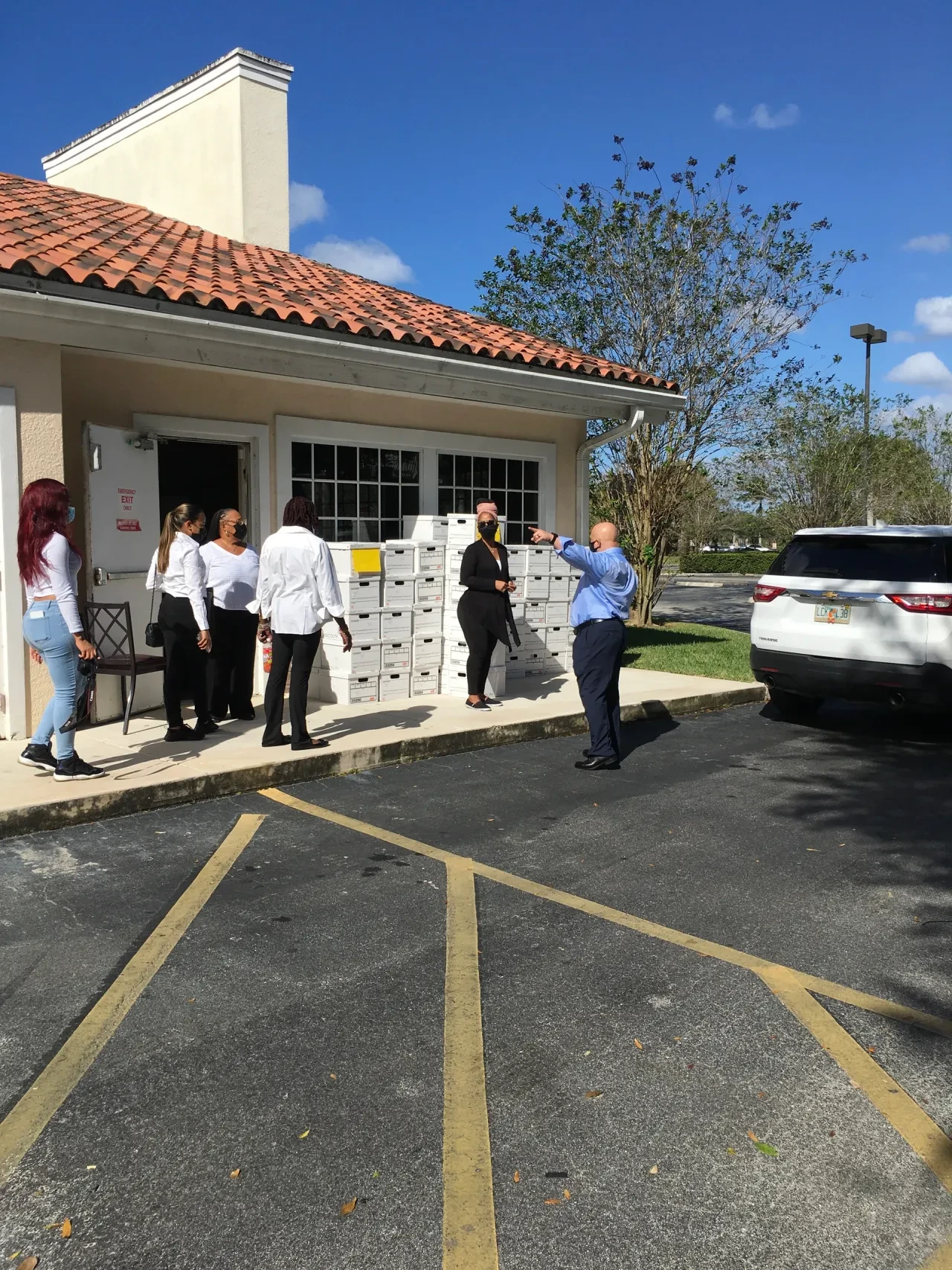 Volunteers directing team outside building with stacked boxes