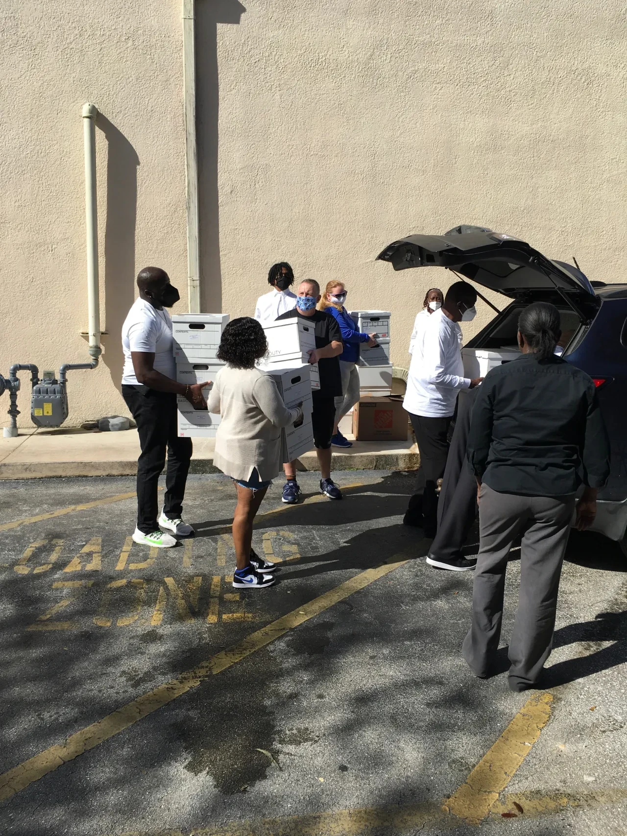 Volunteers passing boxes in loading zone parking lot