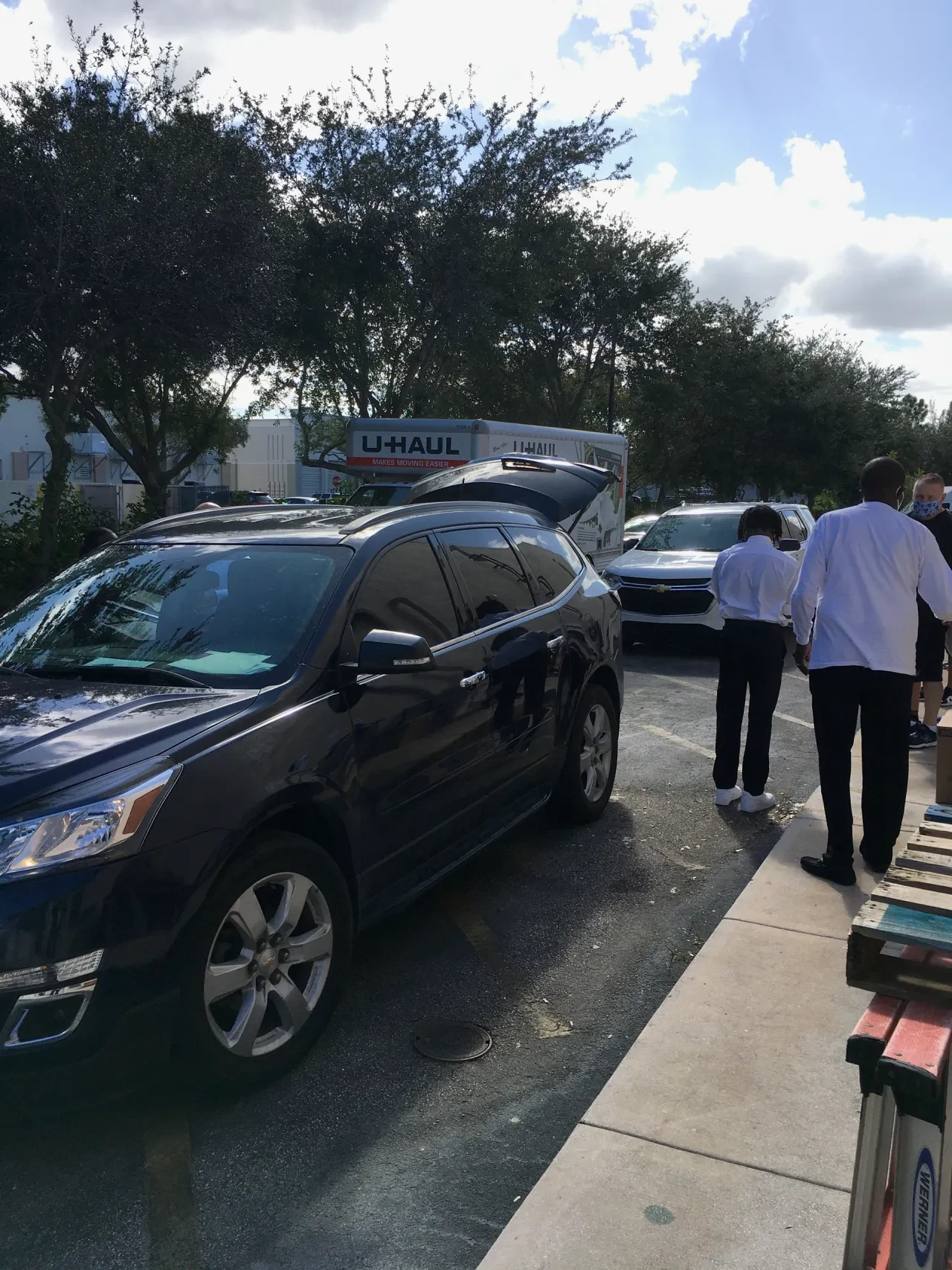 Volunteers and vehicles lined up in parking lot with U-Haul