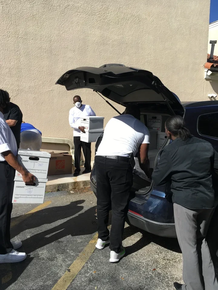 Volunteers loading boxes into vehicle trunk outdoors