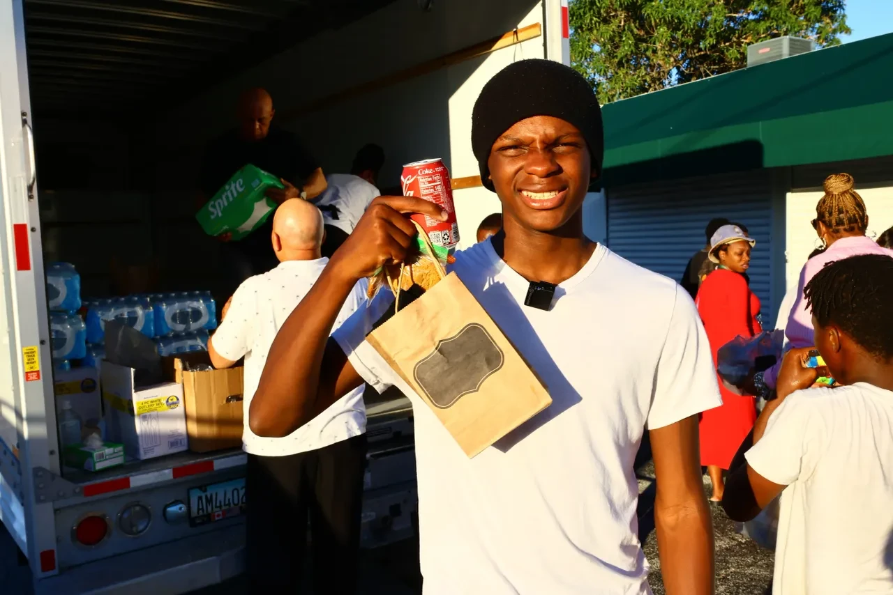 Teen smiling and holding Coke can and paper bag at U-Haul distribution event