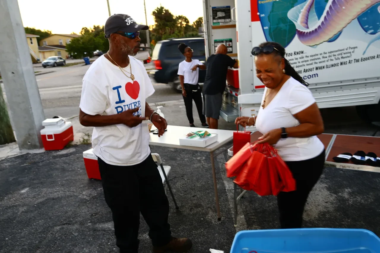 Man and woman chatting and laughing at outdoor community distribution table