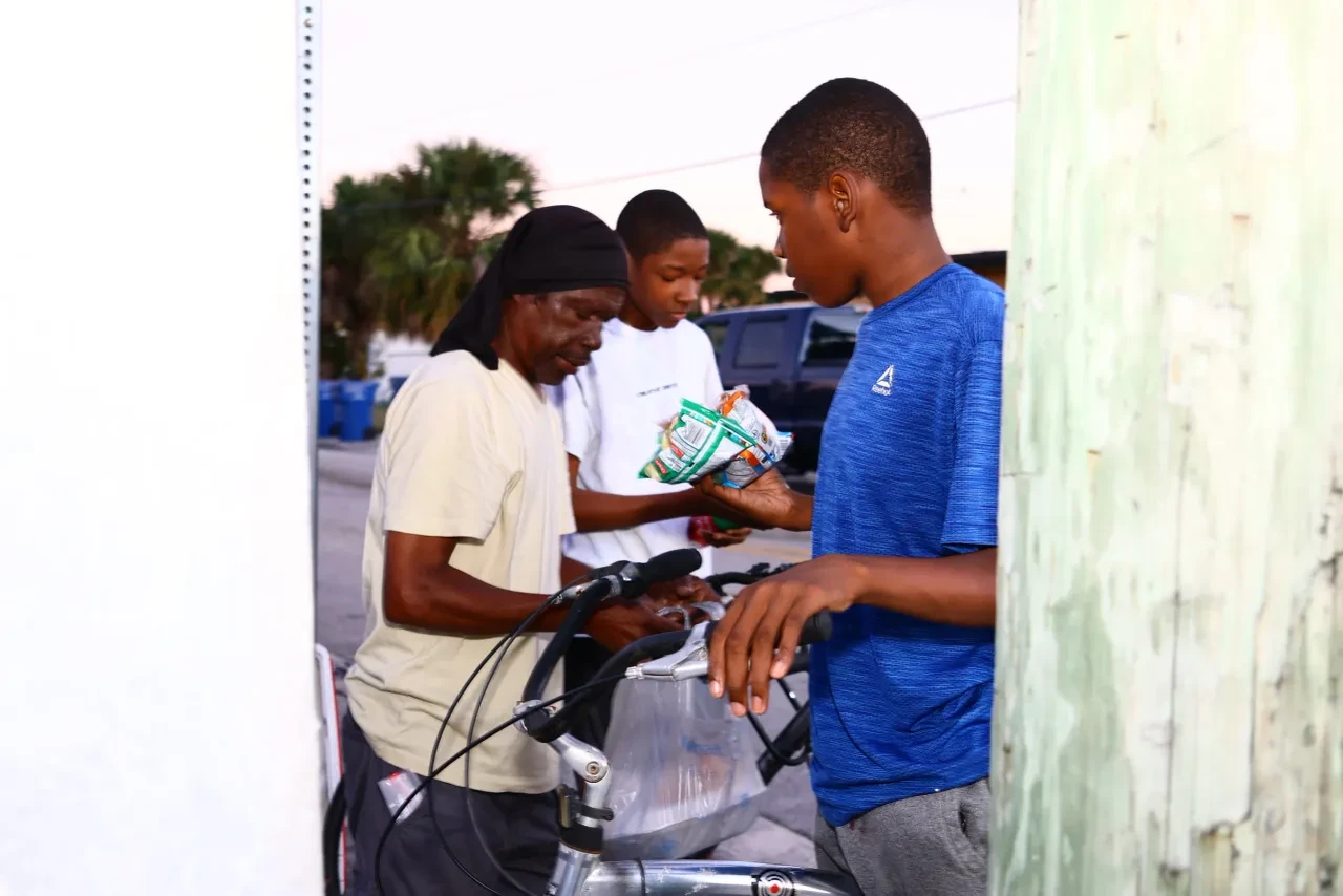 Three people sharing food donations next to bicycles at community event