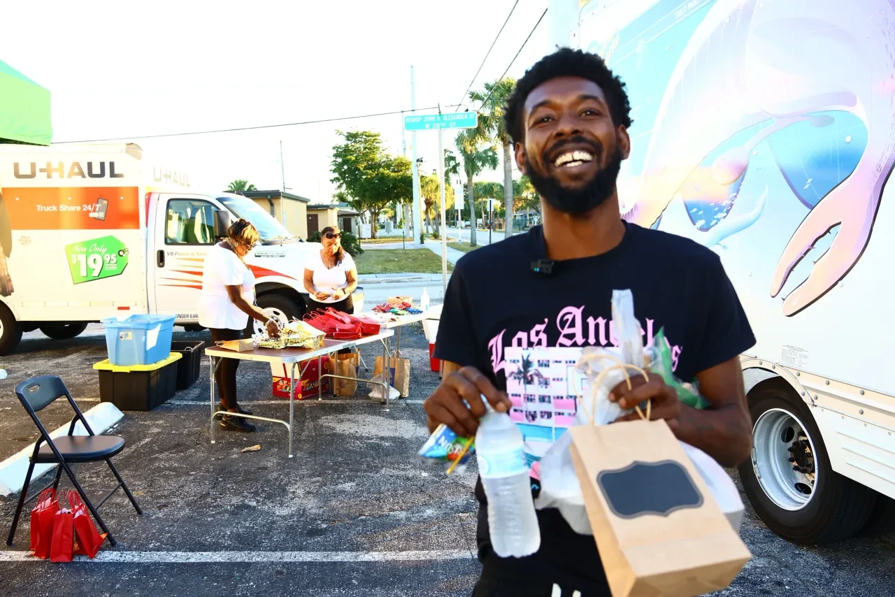 Smiling man in Los Angeles shirt holding gift bag at U-Haul distribution event