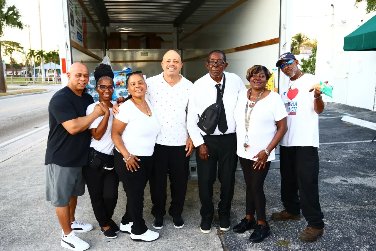 Seven volunteers posing together in front of box truck at community event