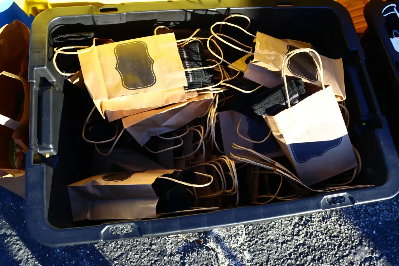 Crate of kraft paper gift bags and black socks ready for distribution