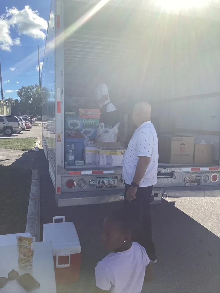 Volunteer and child watching supplies being unloaded from box truck outdoors