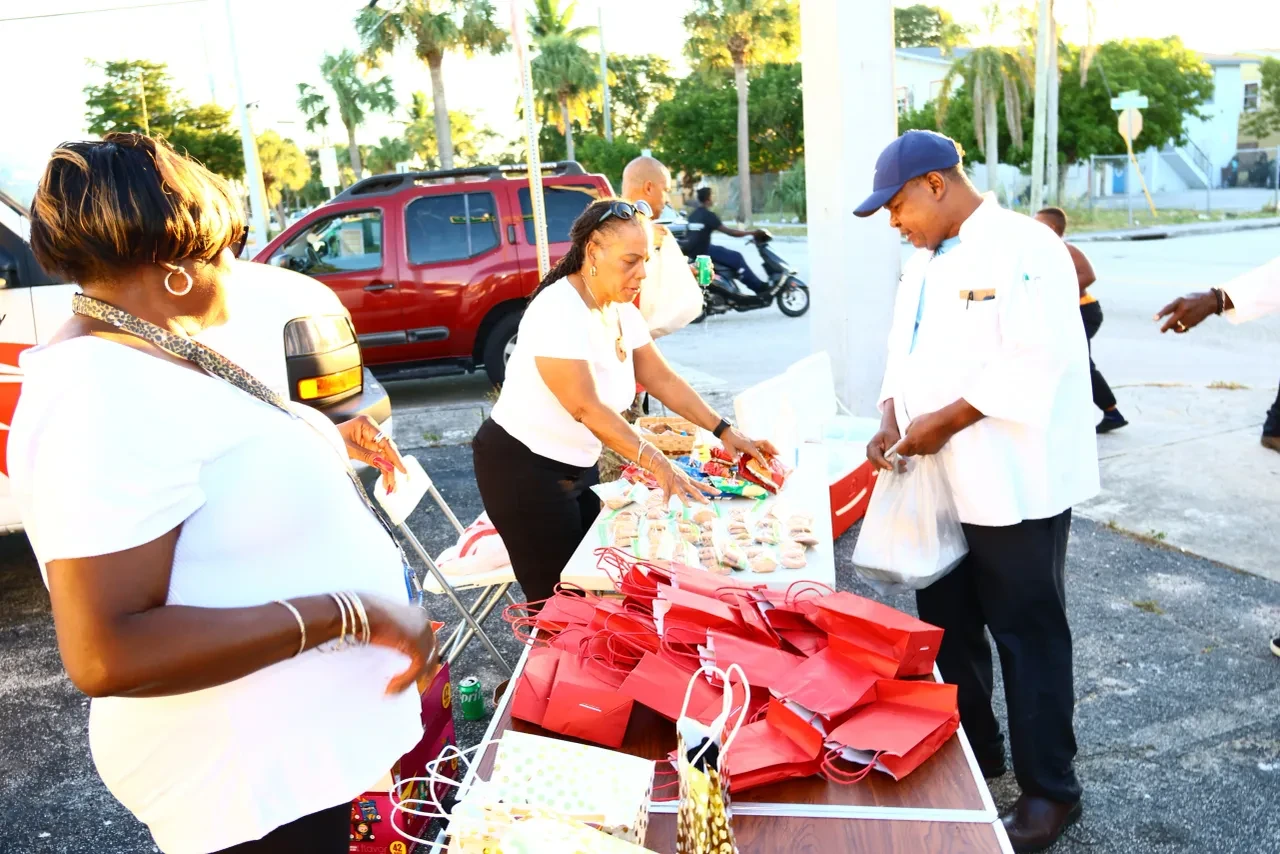 Volunteers distributing red gift bags and food at outdoor community table
