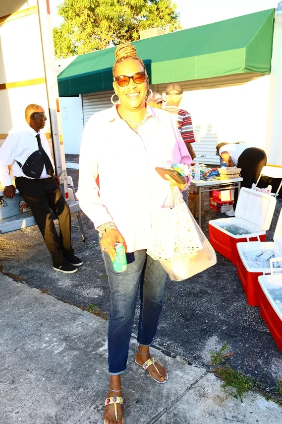 Woman smiling and holding mesh bag at outdoor community distribution table