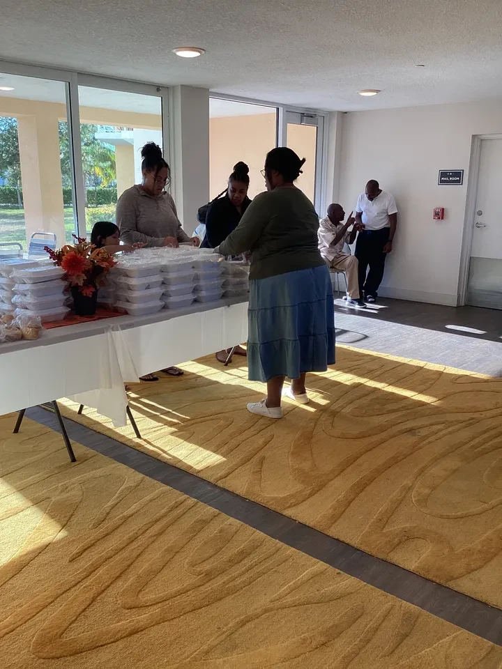 Volunteers serving community members at indoor food distribution table