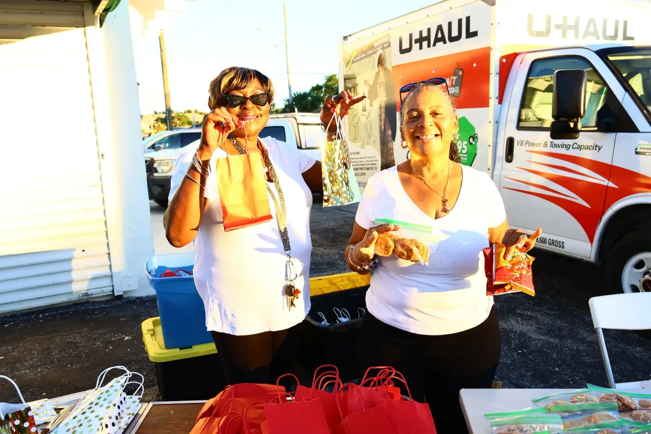 Two women smiling and holding gift bags in front of U-Haul truck