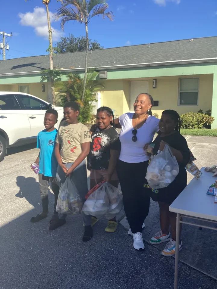 Volunteer and four children holding donation bags at outdoor community event