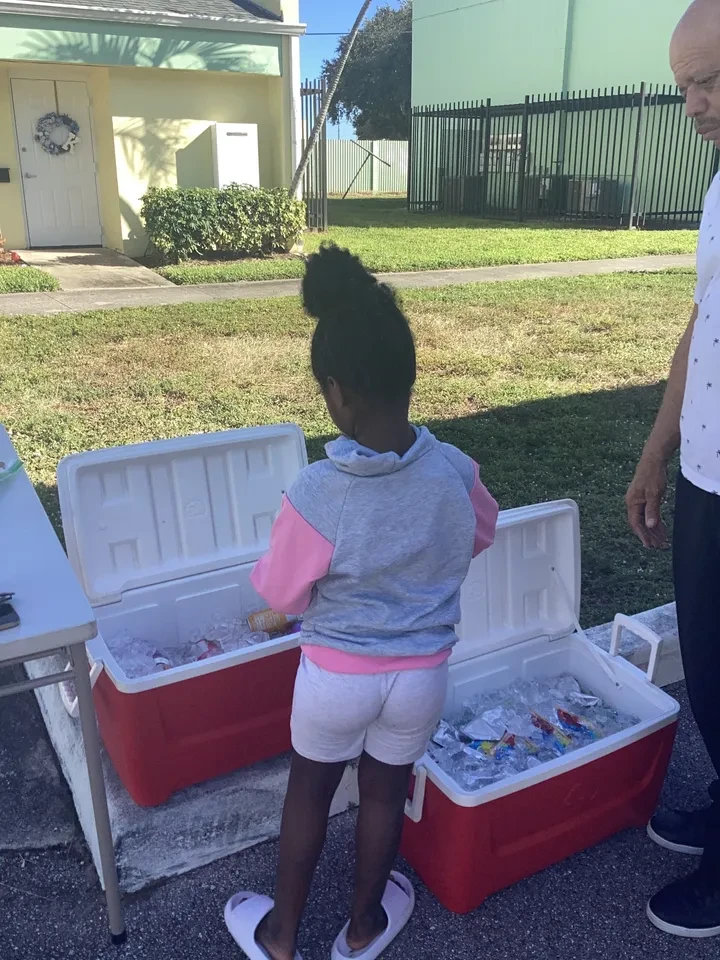Child selecting drinks from open coolers at outdoor community distribution event