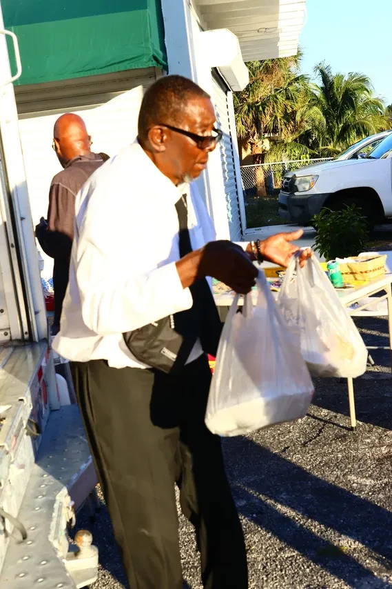 Man carrying grocery bags at outdoor community distribution event