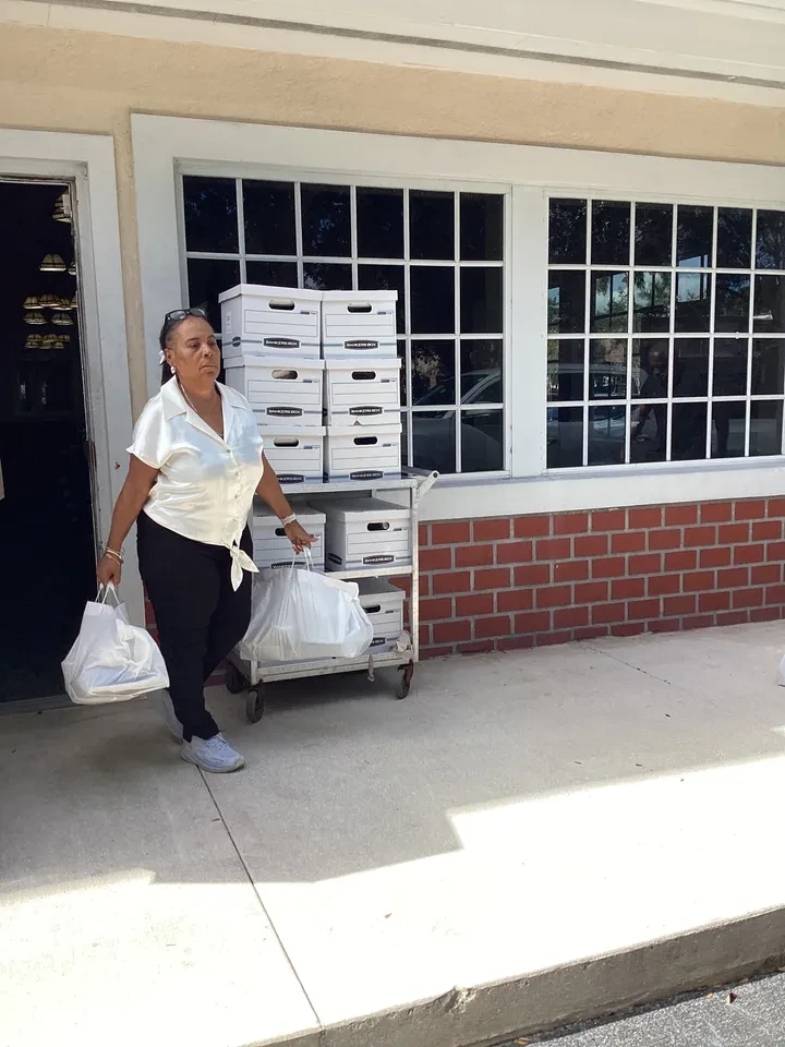Volunteer wheeling bankers boxes outside on cart