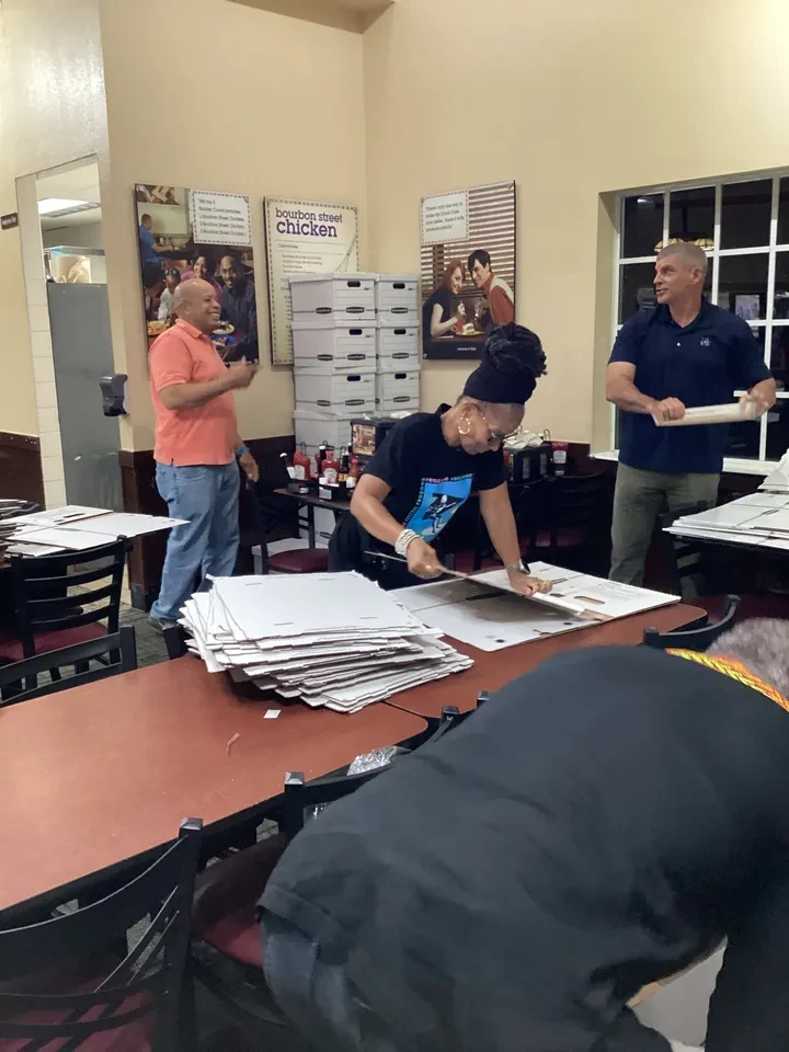 Volunteers assembling food boxes at restaurant tables