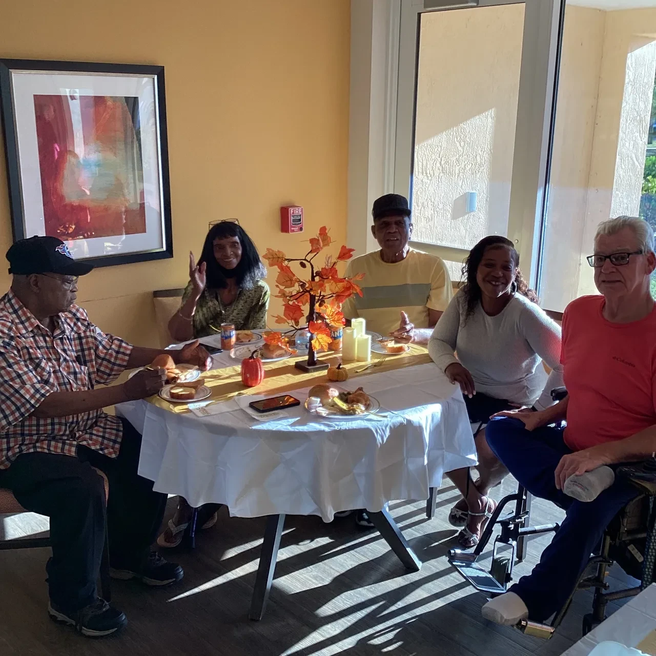 Five community members dining together at fall-decorated table