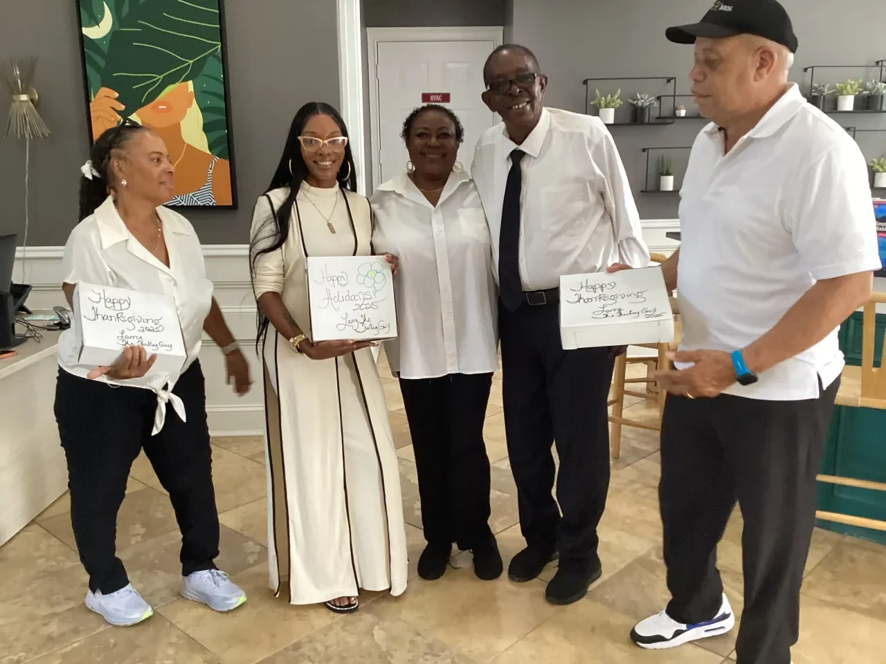 Volunteers holding Happy Thanksgiving gift boxes indoors