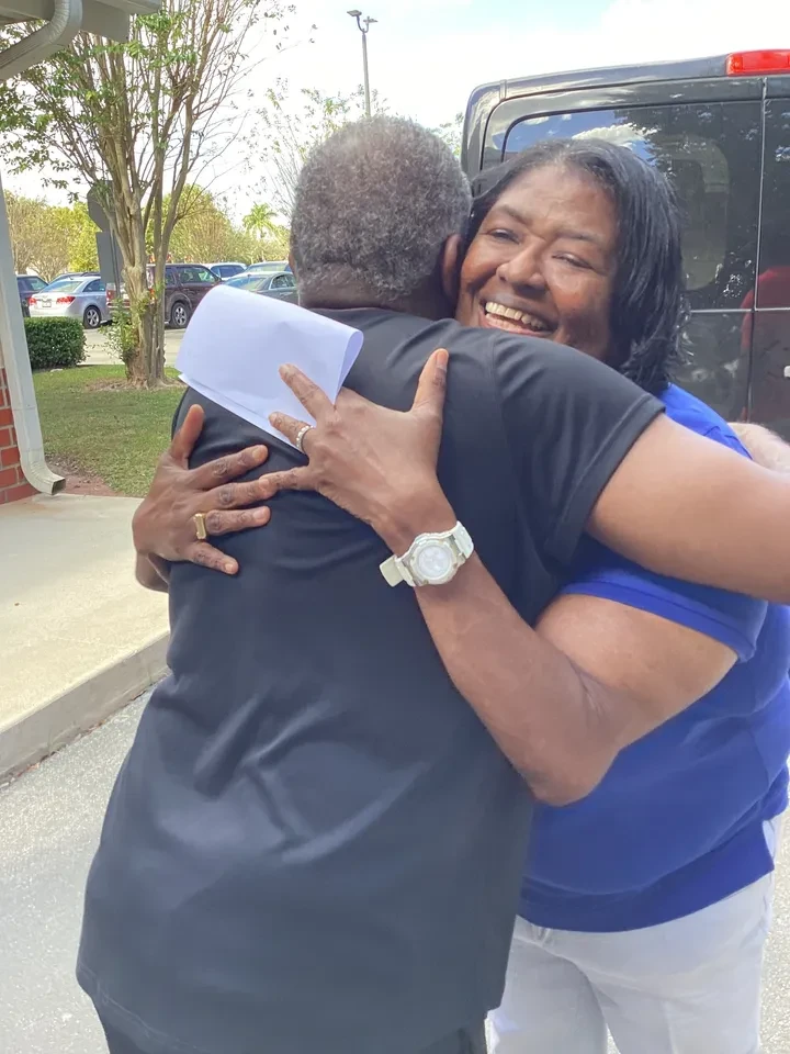 Two community members sharing a warm embrace outdoors