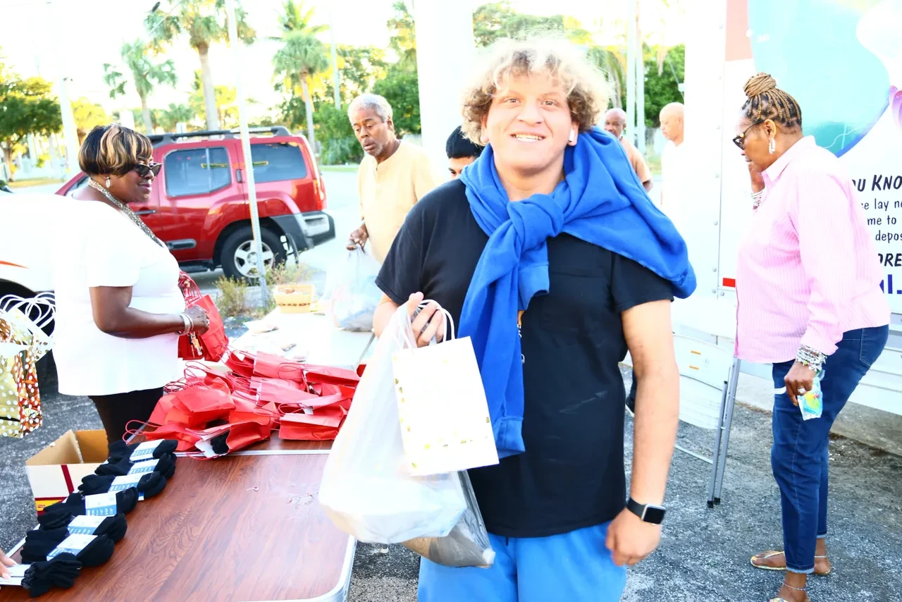Community member smiling while receiving gift bag at outdoor distribution