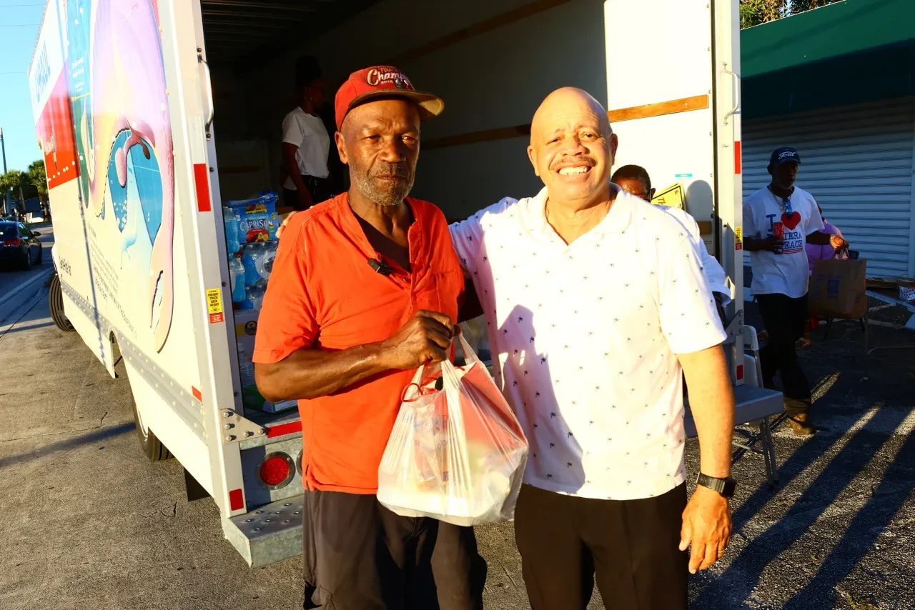 Two men posing together by the distribution truck at community event