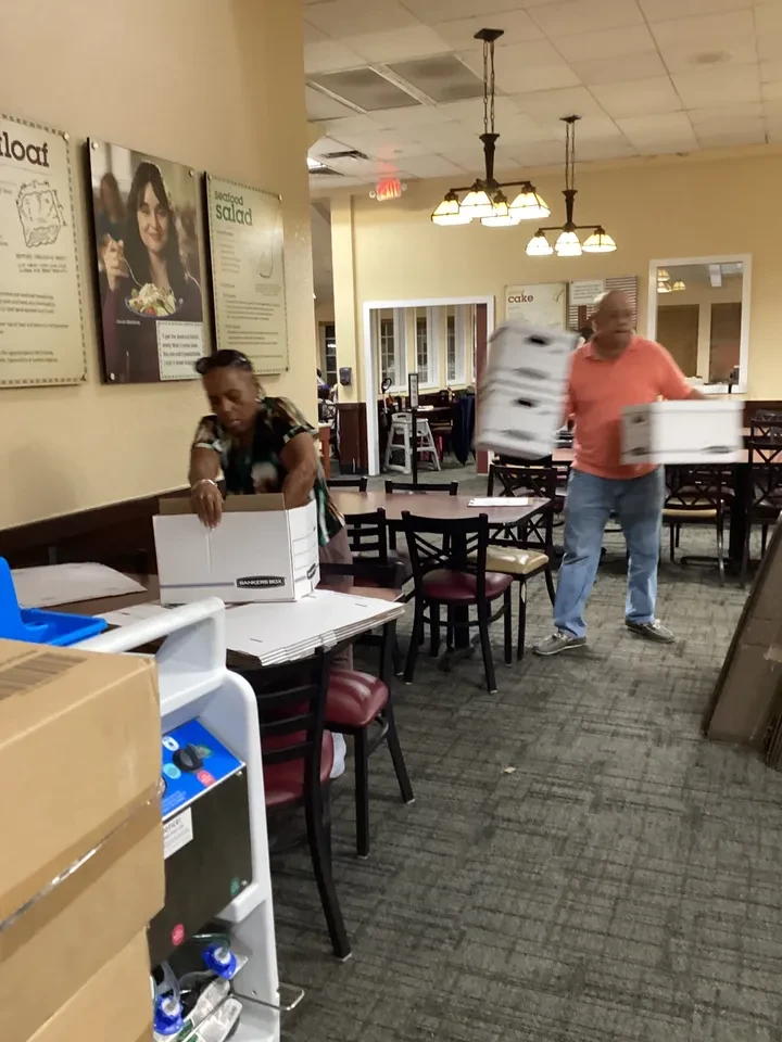 Volunteers assembling banker boxes at restaurant for food distribution