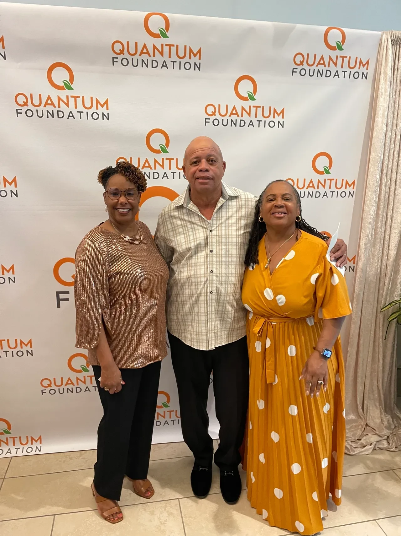Three attendees posing at Quantum Foundation event backdrop