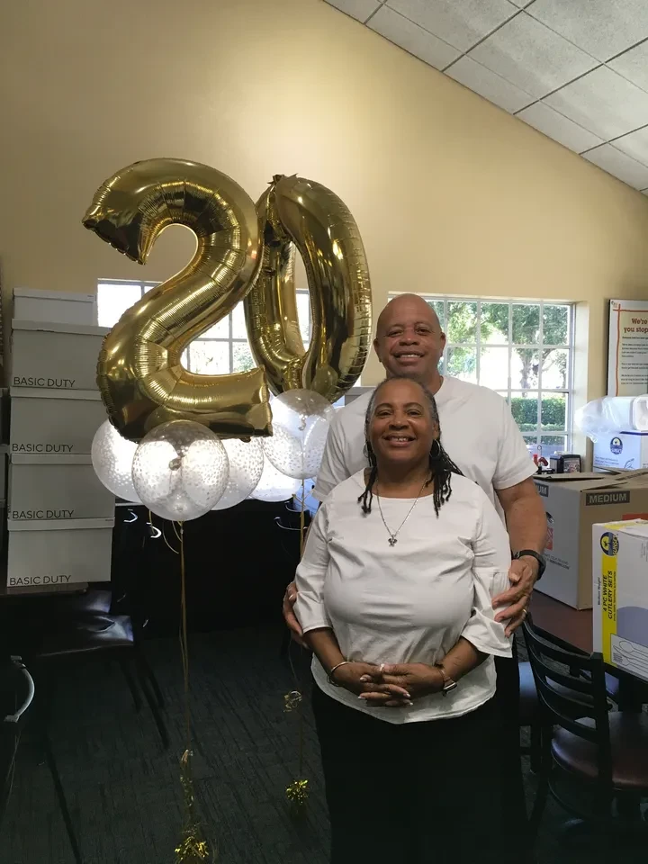 Couple posing with gold "20" balloon display at celebration